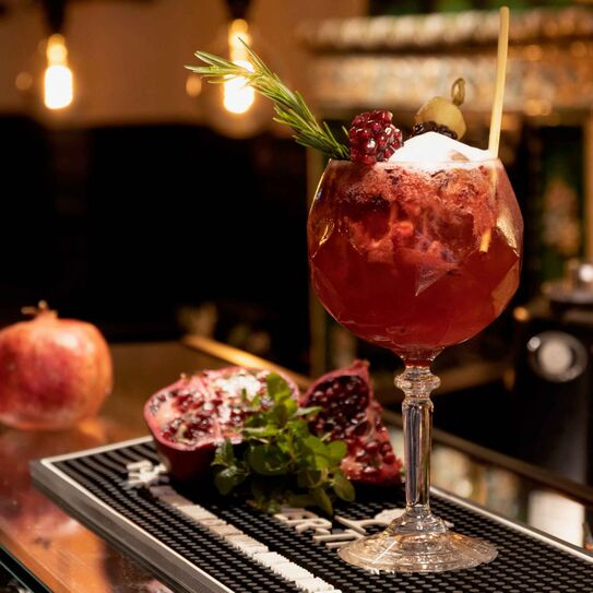 Foto zeigt roten Cocktail, sehr ansprechend dekoriert mit Granatapfel.